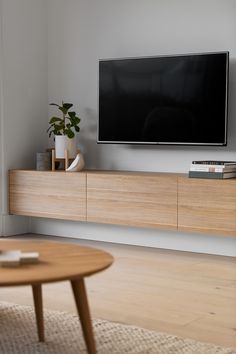 a flat screen tv sitting on top of a wooden entertainment center in a living room