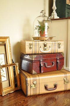 three suitcases stacked on top of each other in front of a mirror and framed photograph