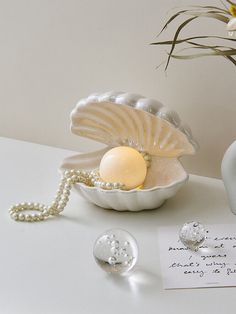 a white vase with pearls and an egg in it next to a note on a table