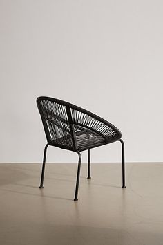 a black chair sitting on top of a hard wood floor next to a white wall