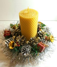 a yellow candle surrounded by pine cones and christmas decorations