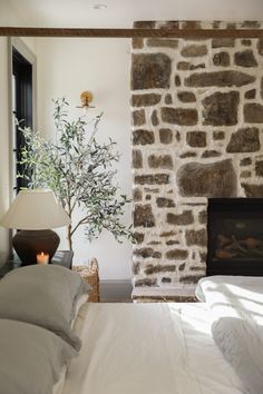 a bedroom with a stone fireplace and white bedding