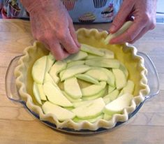 a person cutting apples into small pieces in a pie pan