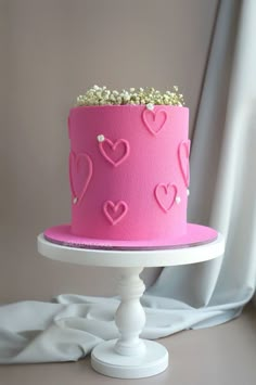 a pink cake decorated with hearts and pearls