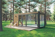 a small wooden cabin in the middle of a green field surrounded by trees and lawn chairs