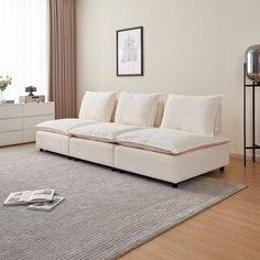 a white couch sitting on top of a wooden floor next to a large gray rug