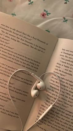 an open book with headphones laying on it's side next to a pair of earbuds