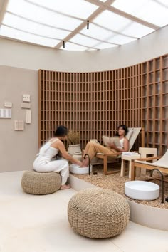 two women sitting on chairs in a room with wood paneled walls and flooring