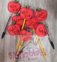 red apples with writing on them sitting on top of some toothpicks in the shape of hearts