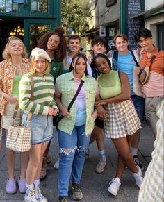 a group of people standing next to each other in front of a building with green doors