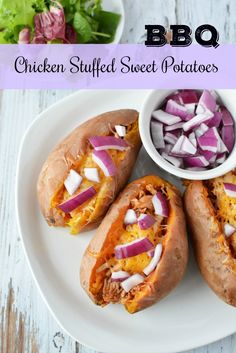 chicken stuffed sweet potatoes on a white plate with red onions in the bowl and lettuce