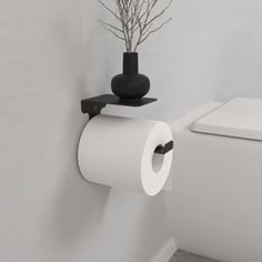 there is a toilet paper roll on the wall next to a vase with flowers in it