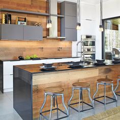 a kitchen with an island and bar stools in front of the counter top that is made out of wood