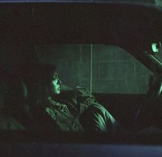 a woman sitting in the back seat of a car at night with her head up