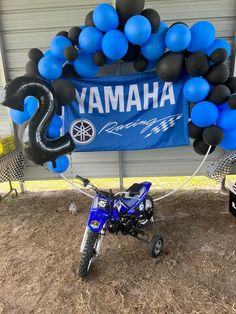 a blue and black motorcycle parked in front of a yamaha sign with balloons attached to it