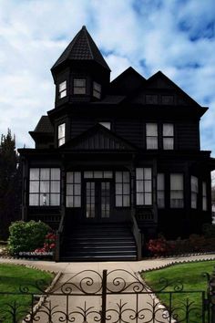 a large black house with lots of windows on it's front porch and stairs leading up to the second floor