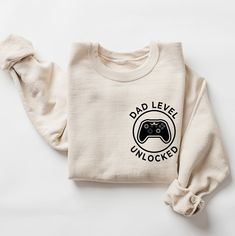 Dad Level Unlocked Sweatshirt, Gaming Dad Shirt, Funny New Dad Shirt, First Time Dad, Gamer Dad Gift, Father's Day Gift, New Father Gift       Hi! Welcome to the LaTeeApparel! It's great to see you here! Our shirts are clean, high quality and soft. It is prepared quickly by our store! Enjoy your shopping! It is a pleasure for us to help you with your questions and you can reach us at any time. F I T  ∙ S I Z I N G  -->Women's sizes are narrower than the waist -->Sleeves are rolled up in some pro Father's Day Cotton Crew Neck Sweatshirt, Casual Crew Neck Tops For Father's Day, Casual Cotton Tops For Father's Day, Long Sleeve Top With Text Print For Father's Day, Father's Day Casual Graphic Sweatshirt, Casual Crew Neck Sweatshirt For Father's Day, Casual Graphic Print Sweatshirt For Father's Day, New Father Gift, New Father