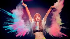 a girl with her arms in the air surrounded by colored powder