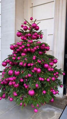 the christmas tree is decorated with pink balls and greenery on it's branches