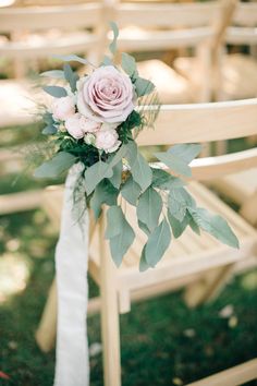 a bouquet of flowers sitting on top of a wooden chair with greenery around it