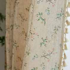 the curtains are lined up with tassels and flowers on them, along with a potted plant