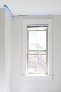 an empty room with white walls and blue tape on the window sill above it