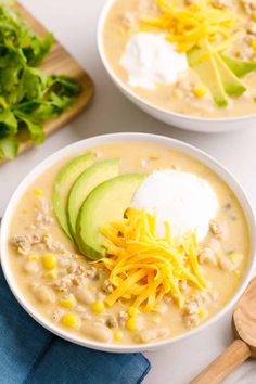 two bowls filled with soup and topped with avocado