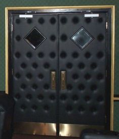 a pair of black chairs sitting in front of a metal door with diamond designs on it