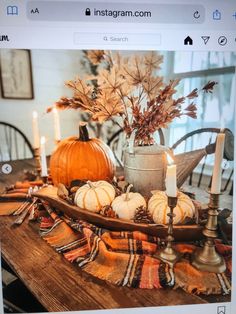 a table topped with pumpkins and candles on top of a wooden dining room table