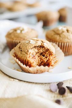 a muffin on a plate with other muffins in the background and scattered chocolate chips