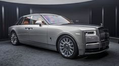 a silver rolls royce parked in front of a black wall