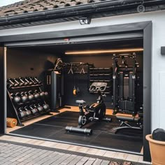 an open garage door showing the inside of a gym with exercise equipment and potted plants