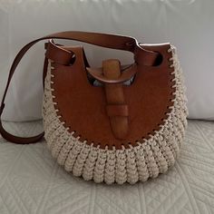 a brown and white handbag sitting on top of a bed next to a pillow