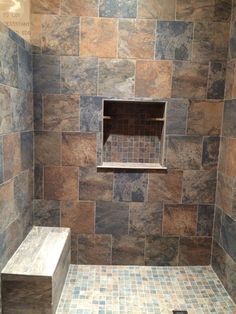 a walk in shower sitting next to a tiled floor and wall with shelves on each side