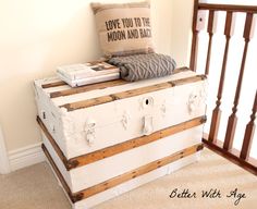 an old trunk is sitting on the floor in front of a stair case with books and a pillow