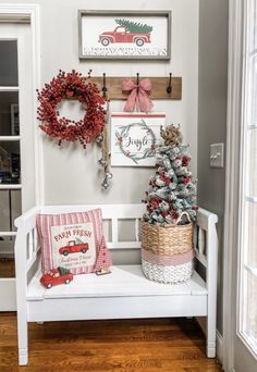 a white bench with christmas decorations and wreaths hanging on the wall above it, along with other holiday decor