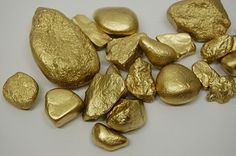 gold nuggets are shown on a white surface