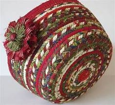 a red and green basket with a flower on the top is sitting on a white surface