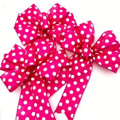 a pink and white polka dot bow on a white background with clippings to the side