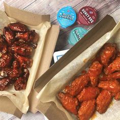 two boxes filled with chicken wings next to some yogurt and blue cheese stickers