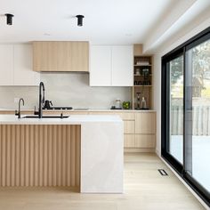 a kitchen with an island counter, sink and sliding glass doors leading to the back yard