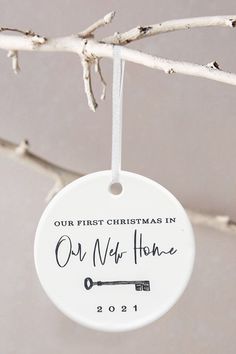 a white ornament hanging from a tree with the words our first christmas in our new home