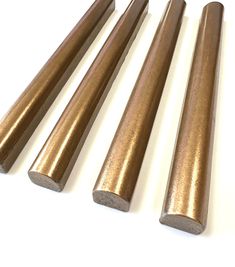 four brass tubes are lined up on a white surface