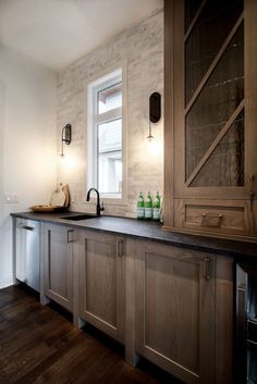 a kitchen with wooden cabinets and black counter tops next to a white wall that has a window