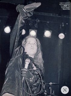 a woman with long hair holding a microphone in front of her head while standing on stage