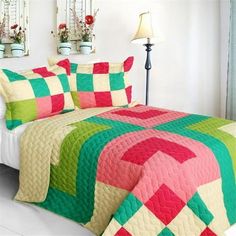 a bed covered in a colorful quilt next to two lamps