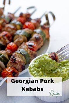 a plate with skewered meat and veggies next to a bowl of pesto sauce