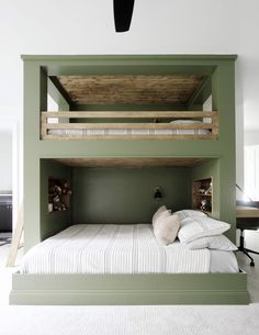 a green bunk bed with two white pillows