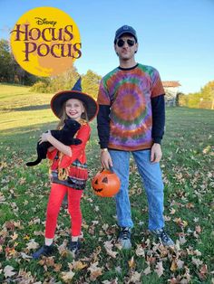 a man and girl dressed up in halloween costumes with pumpkins on the grass, standing next to each other