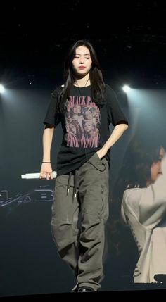 a young man standing on top of a stage with his hands in his pockets and holding a skateboard